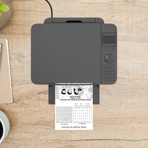 May include: A grey printer producing a black and white activity sheet. The sheet features the text "Joseph Forgives His Brothers", a maze, and an illustration. The printer sits on a wooden surface.