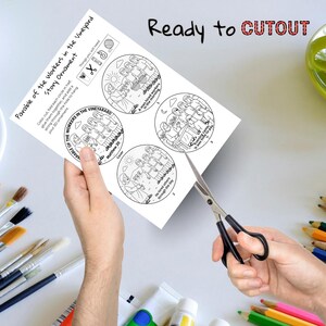 May include: A white paper with a black and white illustration of the Parable of the Workers in the Vineyard story ornament. The text "Ready to CUTOUT" is at the top. Scissors are cutting the paper.