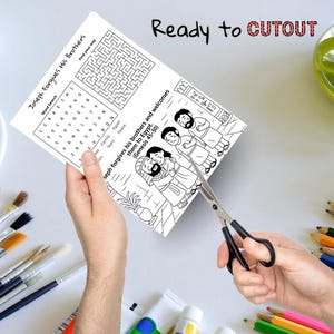 May include: A black and white activity sheet with the text "Joseph Forgives His Brothers" is being cut with scissors. The sheet includes a word search, a maze, and an illustration of a biblical scene. The words "Ready to CUTOUT" are written at the top.
