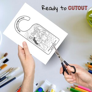 K&ouml;nnte beinhalten: Ein wei&szlig;er T&uuml;rh&auml;nger mit einer Schwarz-Wei&szlig;-Illustration einer biblischen Szene wird mit einer Schere ausgeschnitten. Der Text "Ready to CUTOUT" steht oben. Der Text "Gott braucht Mut zum Retten" steht oben links.