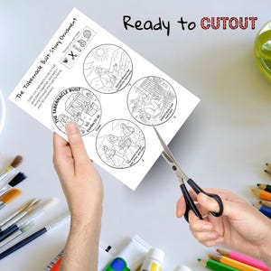 Pode incluir: Uma folha de papel branca com quatro ilustra&ccedil;&otilde;es circulares e texto sobre o ornamento da hist&oacute;ria da constru&ccedil;&atilde;o do Tabern&aacute;culo. O texto "Ready to CUTOUT" est&aacute; escrito em preto e vermelho. Uma tesoura corta o papel. Pinc&eacute;is e l&aacute;pis de cor no fundo.