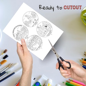May include: A white paper with four circular illustrations and text, including "Paul Preaches in Athens" and "Ready to CUTOUT". A pair of scissors is positioned to cut out the circles. The image is surrounded by art supplies.