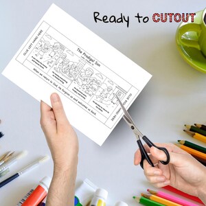 May include: A black and white illustrated activity sheet titled "The Prodigal Son" is being cut with scissors. The sheet has text that reads "Ready to Cutout" and instructions for gluing. Colored pencils, paint tubes, and a green mug are in the background.