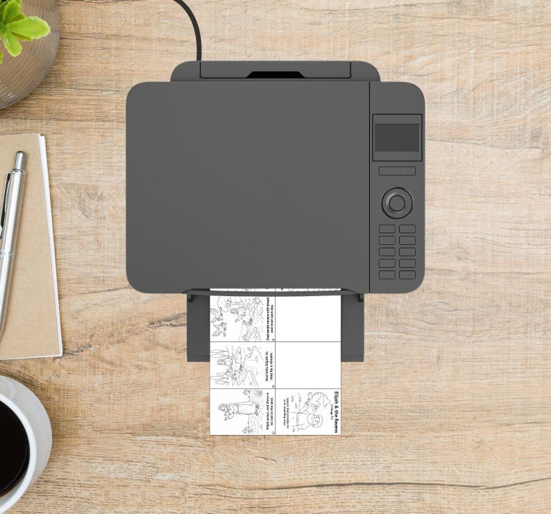 May include: Overhead view of a gray printer with a printed sheet of paper. The paper has four black and white illustrations with text. The printer is on a light brown wooden surface.