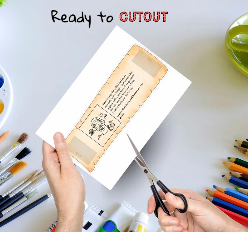 May include: A white paper bookmark with a scroll design, featuring text and a cartoon illustration. The words "Ready to CUTOUT" are at the top. Scissors are cutting the bookmark. Paintbrushes and pencils are in the background.