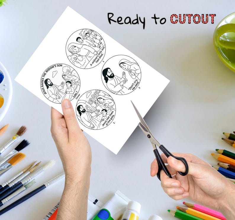 Puede incluir: Una hoja de papel con cuatro ilustraciones circulares que representan escenas b&iacute;blicas, incluido Jes&uacute;s. El texto "Ready to CUTOUT" est&aacute; en la parte superior. Las tijeras est&aacute;n a punto de recortar las ilustraciones. Pinceles y l&aacute;pices de colores en el fondo.
