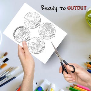 Może przedstawiać: Biała kartka papieru z czterema okrągłymi ilustracjami przedstawiającymi sceny biblijne. Tekst "Ready to CUTOUT" jest wydrukowany u g&oacute;ry. Nożyczki są ustawione do wycięcia k&oacute;ł. Pędzle i kredki w tle.