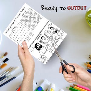 May include: A black and white activity sheet with the text "Joseph Interprets Pharaoh's Dreams" is being cut out with scissors. The sheet includes a word search, a maze, and an illustration of a biblical scene. The words "Ready to CUTOUT" are written at the top.