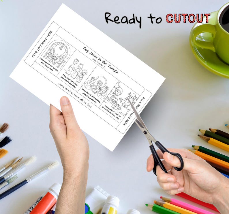 May include: A black and white illustrated activity sheet titled "Boy Jesus in the Temple" is being cut with scissors. The sheet includes text and illustrations depicting a Bible story. The words "Ready to CUTOUT" are written at the top.