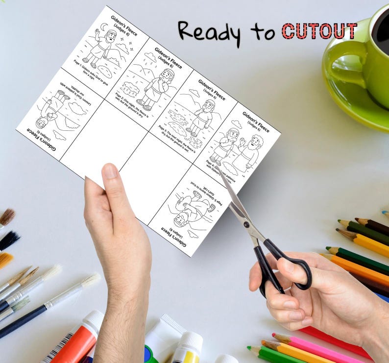 May include: A black and white illustrated cutout sheet titled "Gideon's Fleece" with the text "Ready to CUTOUT". The sheet is being cut with scissors. A green mug and colored pencils are in the background.
