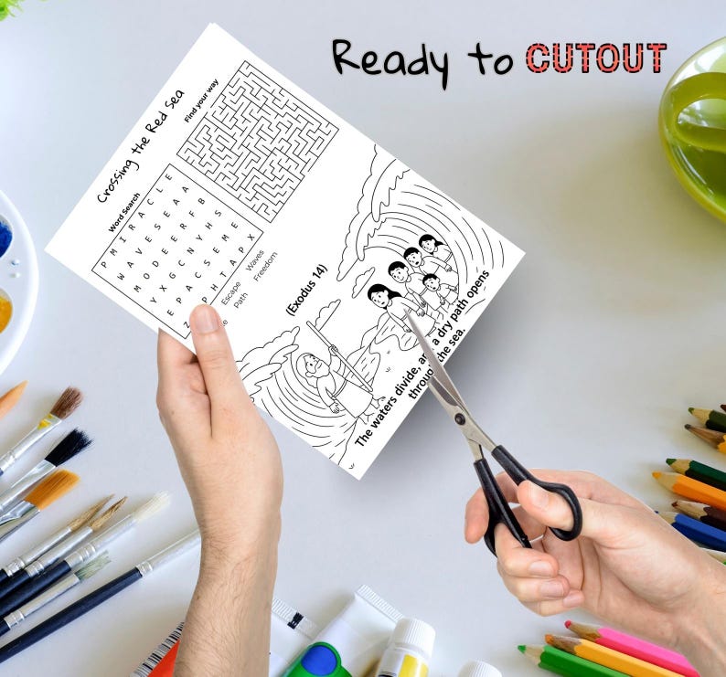 May include: A black and white activity sheet with the text "Crossing the Red Sea" and a word search puzzle. The sheet also features a maze and an illustration of people crossing the sea. Scissors are cutting the sheet.