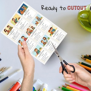 May include: A sheet of illustrated cards with questions and answers, held by a person's hand, being cut with scissors. The cards feature colorful cartoon images and text. The words "Ready to Cutout" are printed at the top.
