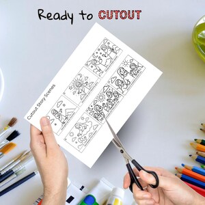 May include: A white sheet of paper with black line drawings of biblical scenes is being cut with scissors. The text "Cutout Story Scenes" and "Ready to CUTOUT" are printed on the paper. The image includes paintbrushes, paint tubes, and colored pencils.