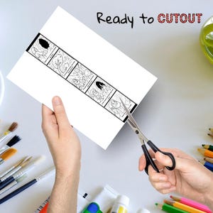 May include: A white sheet of paper with a black and white illustrated strip is being cut with scissors. The strip contains sequential drawings. The text "Ready to CUTOUT" is written at the top in black and red.