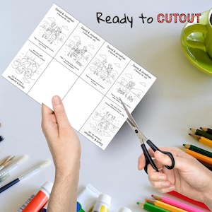 May include: A sheet of paper with black and white illustrations and text, including the words "David & Jonathan" and "Ready to CUTOUT." Scissors are cutting the paper. Colored pencils and paint tubes are in the background.