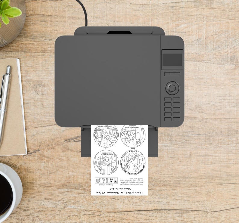 May include: A gray printer is printing a sheet of paper with four circular illustrations and text. The text reads "Emma Rains the Soundmaker's Son Story Ornament". The printer is on a light brown wooden surface.