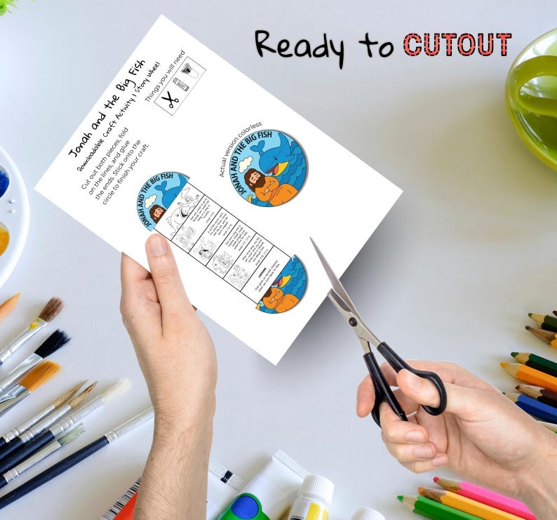 May include: A printable craft activity sheet titled "Jonah and the Big Fish." The sheet includes a story wheel and instructions. The words "Ready to CUTOUT" are printed at the top. A pair of scissors is cutting the paper.