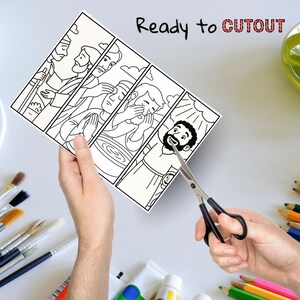 May include: A black and white illustrated print with four panels depicting religious figures. The text "Ready to CUTOUT" is written at the top. A pair of scissors is cutting the print. Paintbrushes, paint tubes, and colored pencils are in the background.