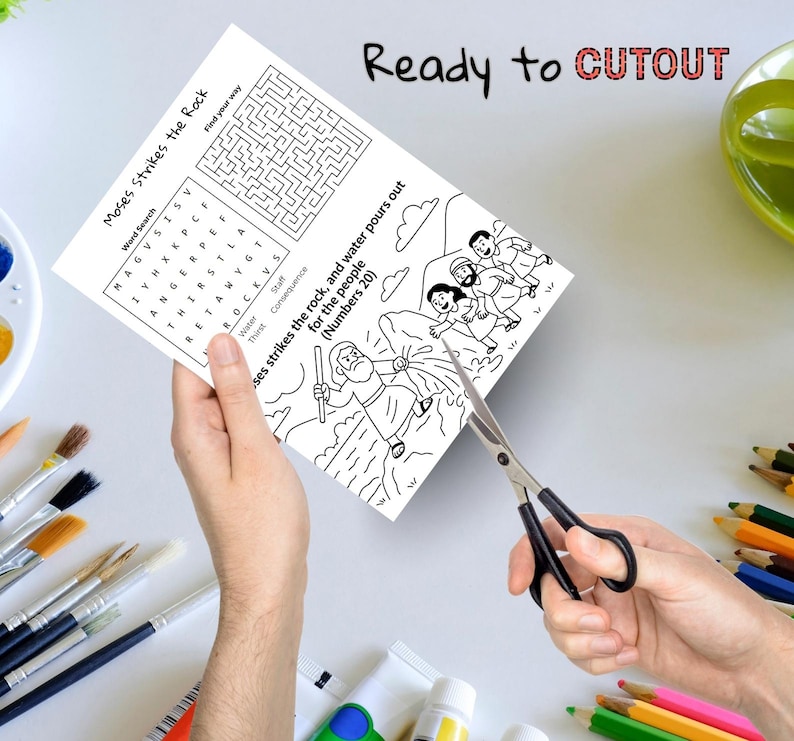 May include: A black and white activity sheet with the text "Moses Strikes the Rock" is being cut with scissors. The sheet includes a word search, a maze, and an illustration of Moses striking a rock. The words "Ready to CUTOUT" are written at the top.