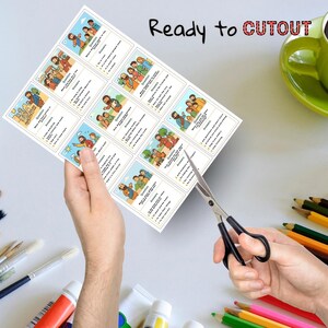 K&ouml;nnte beinhalten: Ein Bogen mit bedruckten Karten mit Illustrationen und Text wird mit einer Schere geschnitten. Die Karten zeigen farbenfrohe Zeichnungen von Menschen und Text. Die Worte "Ready to Cutout" sind oben aufgedruckt. Farbtuben, Pinsel und Buntstifte sind im Hintergrund.