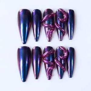 May include: A set of ten artificial nails in a variety of designs. The nails feature a color-shifting effect, transitioning from blue to purple. Some nails are adorned with a 3D purple swirl design, adding a unique touch to the set.