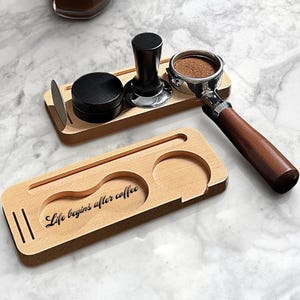 Könnte beinhalten: Holz-Kaffee-Set mit einem Siebträger, einem Tamper und einem kleinen Behälter. Das Set enthält ein Holztablett mit dem Schriftzug "Life begins after coffee". Der Siebträger hat einen Holzgriff.