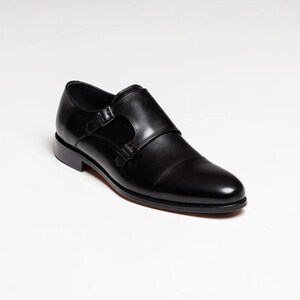 Puede incluir: Zapatos de vestir de cuero negro con doble hebilla monje y punta puntiaguda.