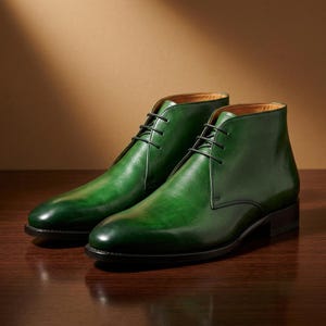 May include: A pair of ankle-high boots in a deep emerald green leather with a polished finish. These boots feature a rounded toe, a lace-up closure with thin black laces, and a low stacked heel. The interior lining is a tan leather material.