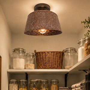 May include: A walk-in pantry featuring white L-shaped shelves organized with glass jars, wicker baskets, and white ceramic canisters labeled Sugar, Flour, Tea, and Bread. A dark metal flush-mount light fixture with a patterned shade hangs above.