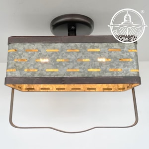 May include: A rectangular ceiling light fixture with a galvanized metal shade and a dark brown metal frame. The shade has horizontal slotted openings. The fixture is suspended from a dark brown circular base.
