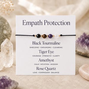 Puede incluir: Una pulsera de cordón negro con cuatro cuentas de piedras preciosas: turmalina negra, ojo de tigre, amatista y cuarzo rosa. La pulsera se muestra en una tarjeta blanca con las palabras "Empath Protection" y los nombres y propiedades de las piedras.