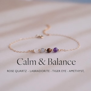 Pode incluir: Uma delicada pulseira dourada com contas de pedras preciosas coloridas: quartzo rosa, labradorita, olho de tigre e ametista. A pulseira é presa a uma fina corrente de ouro. A imagem inclui o texto "Calm & Balance".