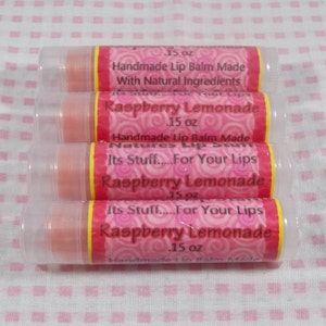 May include: Four pink lip balm tubes with yellow lids. Each tube has a pink and white label with the text "Raspberry Lemonade" and "Its Stuff.....For Your Lips". The label also says "Handmade Lip Balm Made With Natural Ingredients" and "1.5 oz".