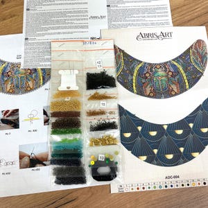 K&ouml;nnte beinhalten: Ein Perlen-Set f&uuml;r eine Halskette mit einem farbenfrohen K&auml;fer-Design. Das Set enth&auml;lt ein Muster, Perlen in verschiedenen Farben und Nadeln. Das Muster zeigt einen farbenfrohen K&auml;fer mit einem blauen, gr&uuml;nen und gelben Design. Die Perlen befinden sich in kleinen Plastikt&uuml;ten, die mit Nummern beschriftet sind. Das Set ist mit "ADC-004" gekennzeichnet.