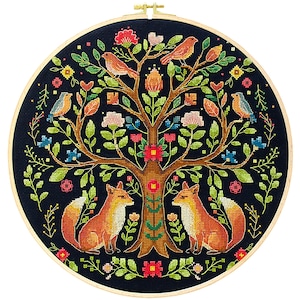 Pode incluir: Um bordado em ponto cruz com uma árvore com pássaros e raposas. O desenho inclui uma árvore castanha com folhas verdes, flores vermelhas e rosas e pássaros laranja. Duas raposas estão sentadas na base da árvore, com um fundo azul escuro.