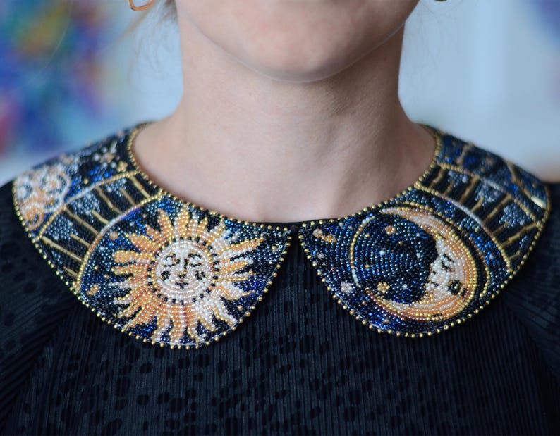 May include: A black collar with a beaded design featuring a sun and moon motif. The beads are in shades of blue, gold, and white.