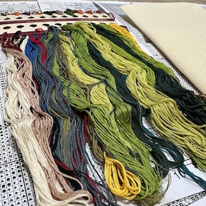 May include: A close-up of a variety of embroidery floss spools in different colors, including green, yellow, blue, red, and white. The floss is arranged in rows and is ready for use in a cross-stitch project.