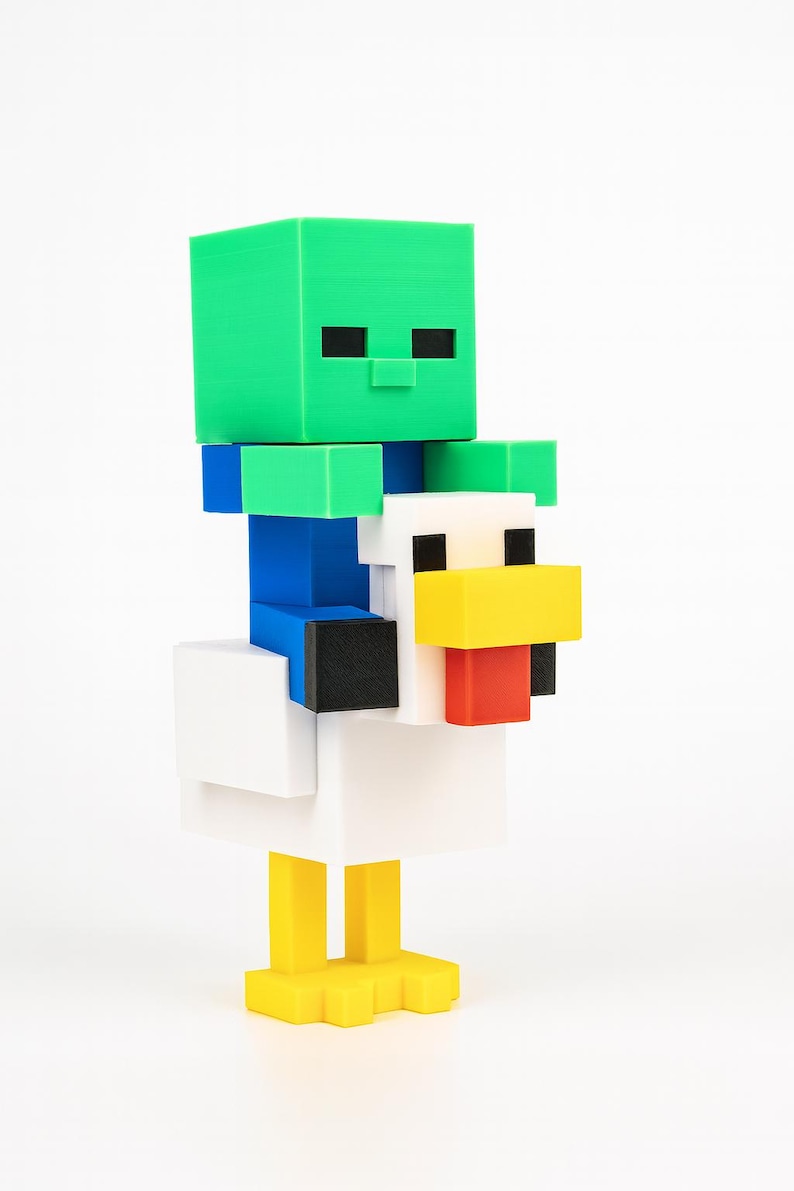 K&ouml;nnte beinhalten: Eine 3D-gedruckte Minecraft-Figur eines gr&uuml;nen Zombies, der auf einem wei&szlig;en Huhn reitet. Der Zombie hat schwarze Augen und sitzt auf einem Huhn mit gelbem Schnabel und F&uuml;&szlig;en. Die Figur besteht aus verschiedenfarbigen Bl&ouml;cken.