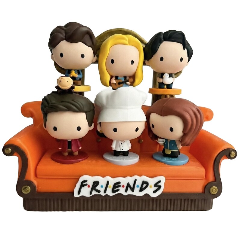Pu&ograve; includere: Un set di statuette raffiguranti sei personaggi dei cartoni animati della serie TV "Friends" su un divano arancione. Il divano ha la scritta "FRIENDS" sul davanti. Ogni personaggio ha una posa, un'acconciatura e un abbigliamento unici.