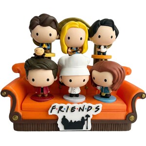 Pu&ograve; includere: Un set di statuette raffiguranti sei personaggi dei cartoni animati della serie TV "Friends" seduti su un divano arancione. Il divano ha una base marrone e il logo dello show &egrave; esposto sul davanti. Ogni personaggio &egrave; in una posa unica.