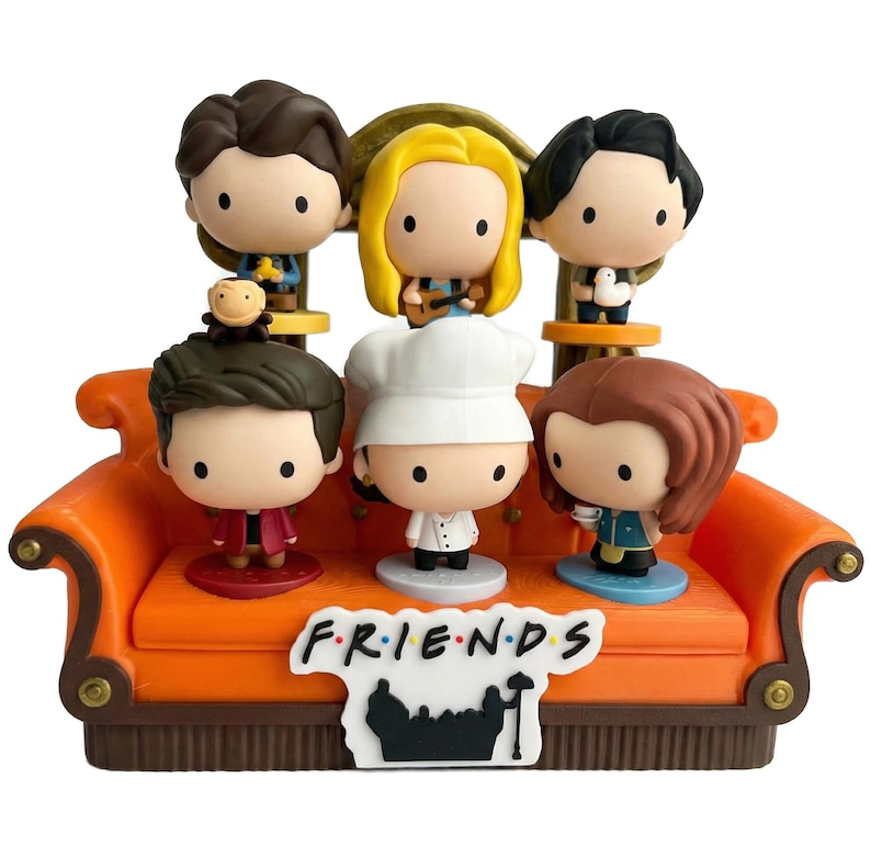 Pu&ograve; includere: Un set di statuette raffiguranti sei personaggi dei cartoni animati della serie TV "Friends" seduti su un divano arancione. Il divano ha una base marrone e il logo dello show &egrave; esposto sul davanti. Ogni personaggio &egrave; in una posa unica.