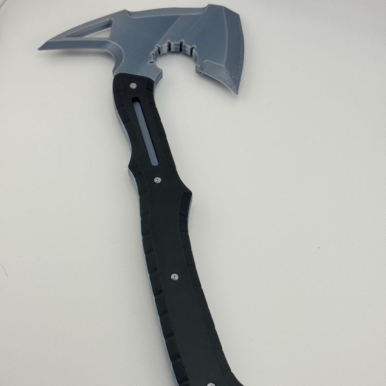 May include: A gray and black axe with a unique design. The axe head is gray with a triangular opening and a curved blade. The handle is black with silver rivets.