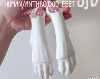 May include: A pair of white SLA 3D printed extra human/anthro dog feet for BJD dolls, suspended by a pink ribbon. The text SLA 3D PRINTED EXTRA HUMAN/ANTHRO DOG FEET BJD and FOR BJD DOLLS BY GA.GA.RU.RU is printed on the image.