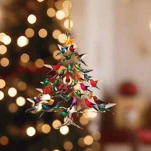 May include: A Christmas tree ornament shaped like a tree, adorned with colorful hummingbird figurines. The ornament is suspended by a gold string and topped with a gold star. The hummingbirds are various colors, including red, green, blue, and yellow.