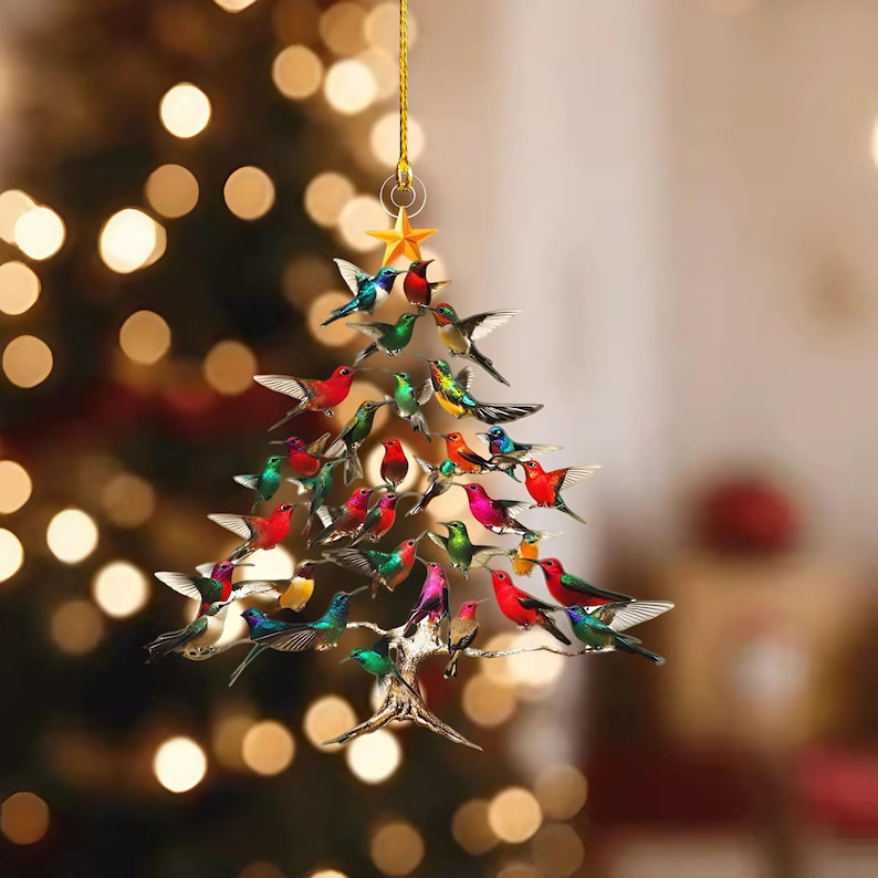 May include: A Christmas tree ornament shaped like a tree, adorned with colorful hummingbird figurines. The ornament is suspended by a gold string and topped with a gold star. The hummingbirds are various colors, including red, green, blue, and yellow.