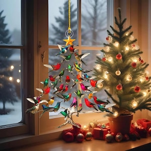 May include: A Christmas tree decoration shaped like a tree, made of colorful hummingbird figurines. The birds are in various colors, including red, green, blue, and pink. A small Christmas tree with lights and ornaments is next to the hummingbird tree.