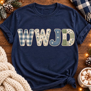 May include: A navy blue short-sleeve t-shirt featuring the letters WWJD across the chest. Each letter has a distinct fabric-like pattern: the first W is blue gingham, the second W is floral, the J is denim with stars, and the D is a green plaid.