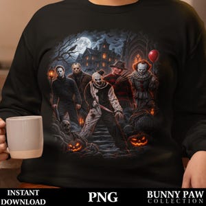 May include: A black long-sleeve sweatshirt featuring a graphic print of five horror movie characters standing in front of a dark mansion at night. The design includes pumpkins, a red balloon, and a graveyard scene with a full moon in the background.