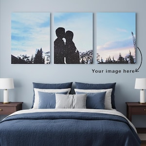 May include: Triptych canvas art featuring a silhouette of a couple kissing against a blue sky with trees. The text "Your image here" is below the artwork. The artwork is displayed above a bed with blue bedding and pillows.