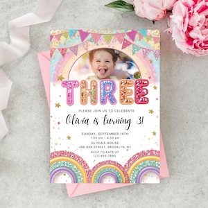 Puede incluir: Una invitación de cumpleaños colorida con una foto de un niño, la palabra "THREE" en letras brillantes y el texto "Olivia is turning 3!". La invitación incluye detalles del evento y un diseño de arcoíris y estrellas.